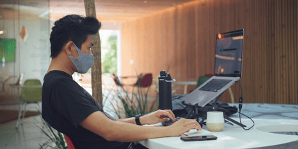 man working in office with mask laptop